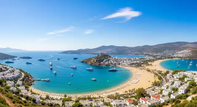 Bodrum'un en güzel plajlarını Come Rent konforuyla keşfedin. Geniş açılı bu fotoğrafta masmavi deniz ve sahil şeridi görülüyor.