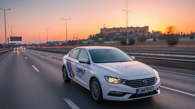 Gaziantep otoyolunda gün batımında hızla ilerleyen, kapısında Come Rent logosu bulunan beyaz kiralık araç. Arka planda şehrin silueti ve tarihi yapılar görünüyor.