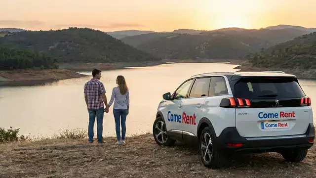 Come Rent ile Özgürlüğü Keşfet Gün batımında göl manzaralı bir tepede manzarayı izleyen çift ve yanlarında Come Rent logolu beyaz SUV kiralık araç.