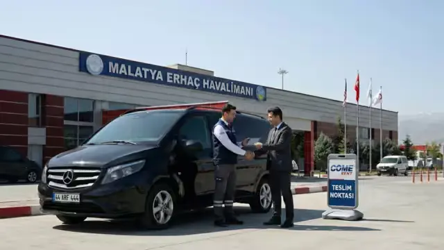 Come Rent personeli, Malatya Erhaç Havalimanı terminal binası önünde siyah Mercedes-Benz Vito aracı müşteriye teslim ediyor.