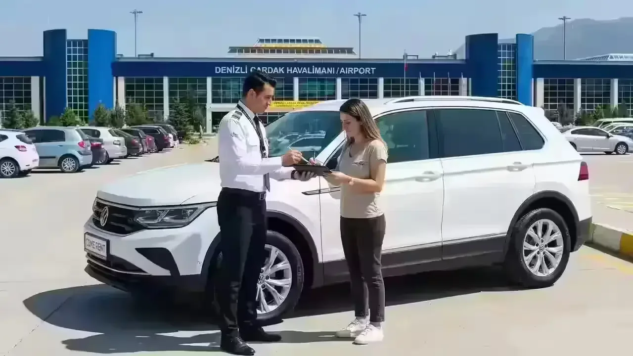 Vor dem Terminalgebäude des Flughafens Denizli Çardak lassen Mitarbeiter von Come Rent eine Kundin, die gerade einen weißen SUV abgeholt hat, das Fahrzeug digital per Tablet signieren.